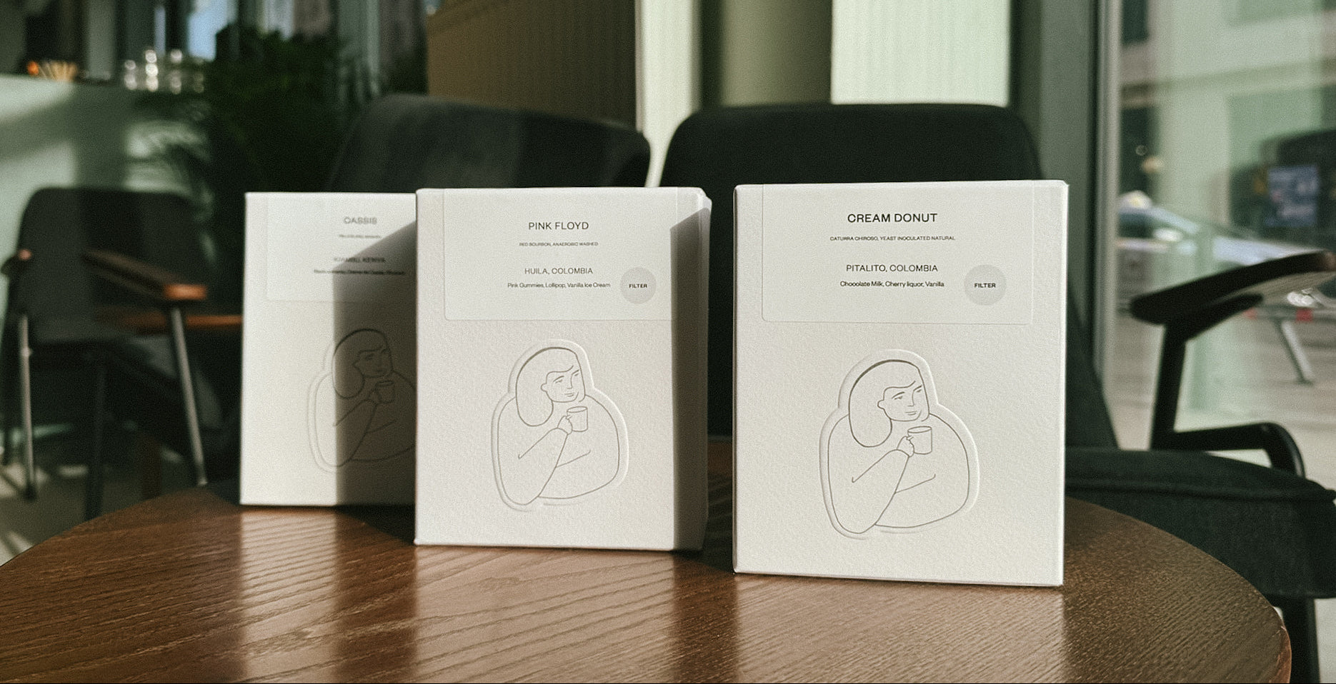 Three white boxes with branding on a wooden table in an indoor setting