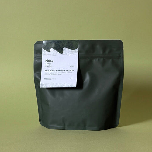 A matte black stand-up pouch of Moss Coffee Roasters on a solid olive green background.